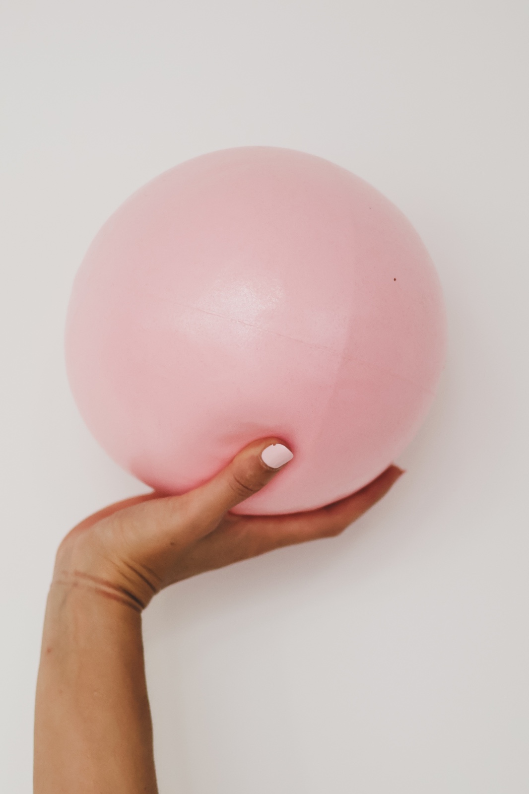Mano sujetando una pelota de pilates rosa