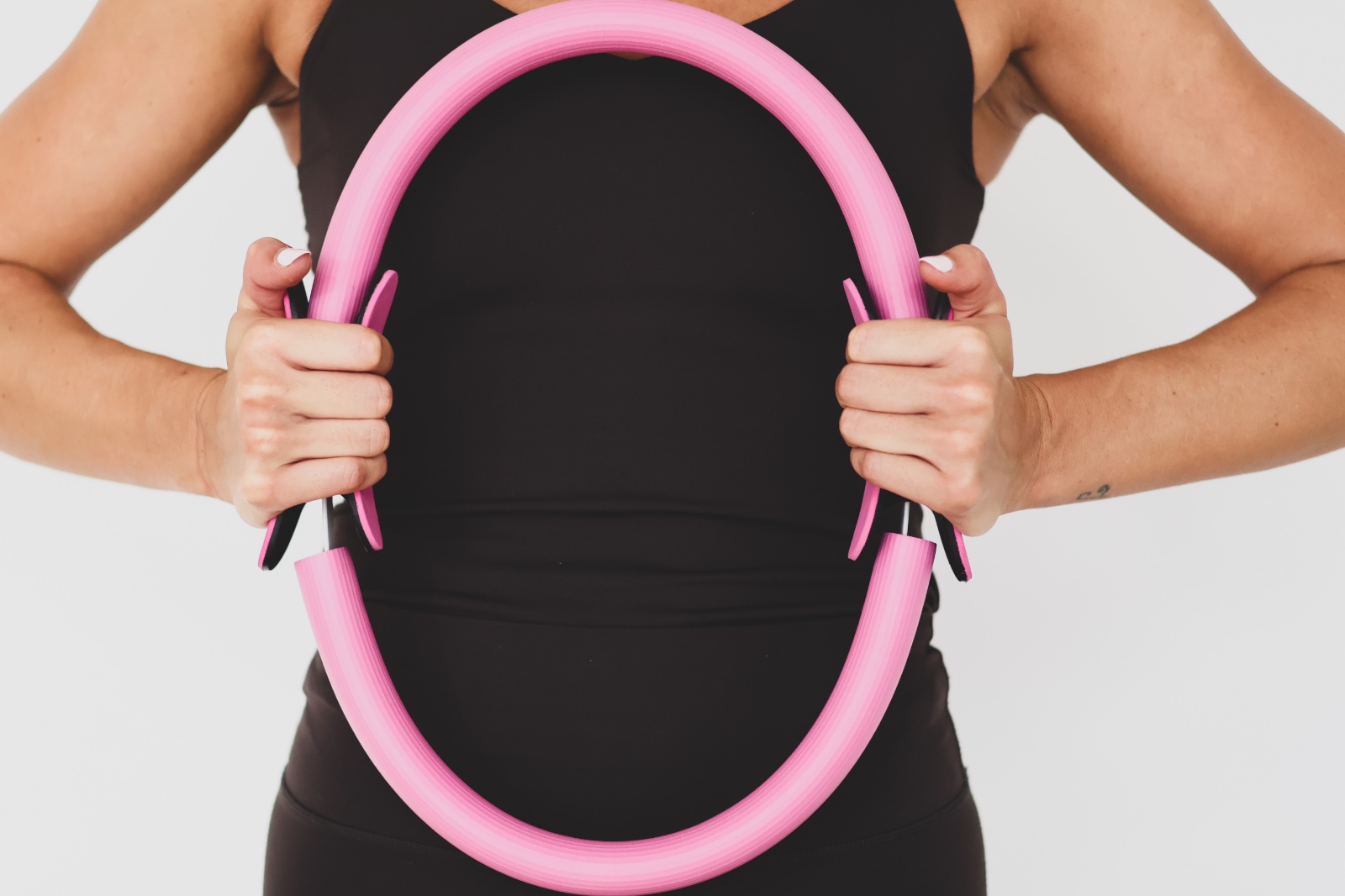 Aro de pilates rosa sujeto con ambas manos
